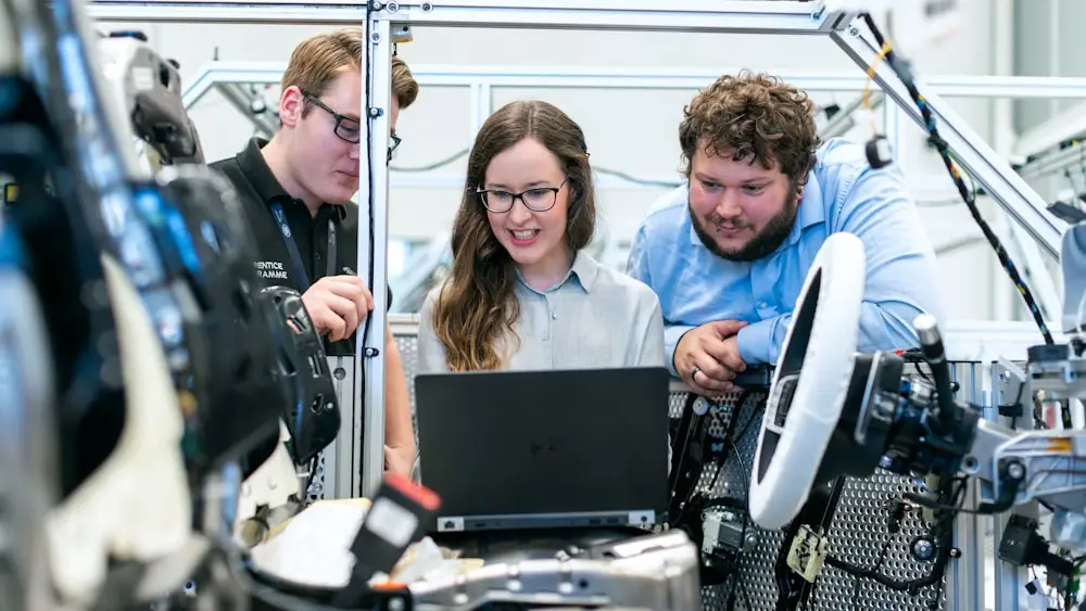 Three engineers reading test data from a laptop at a rig