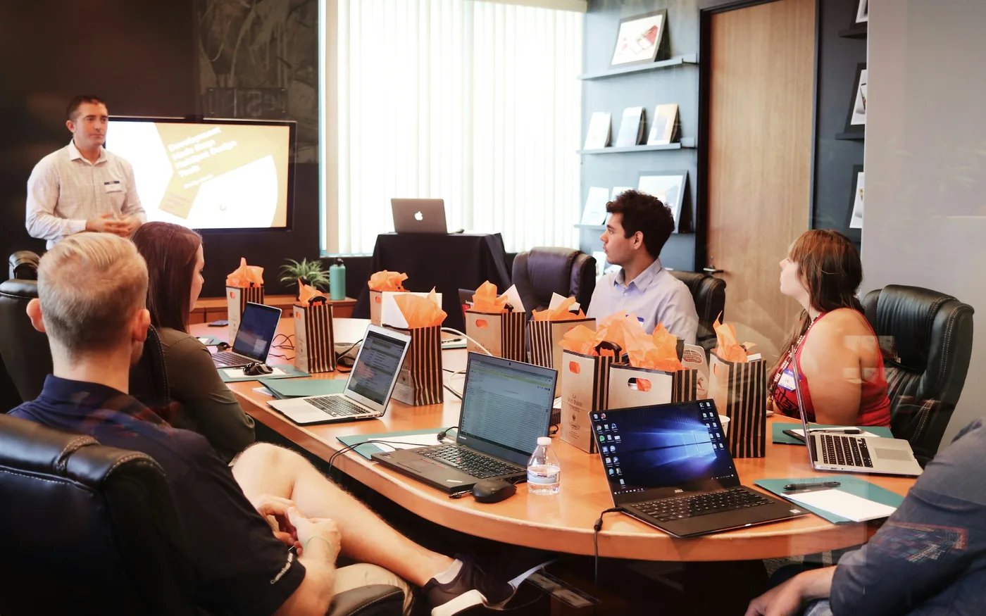 A cohort in a training room with laptops open, facing a presenter.