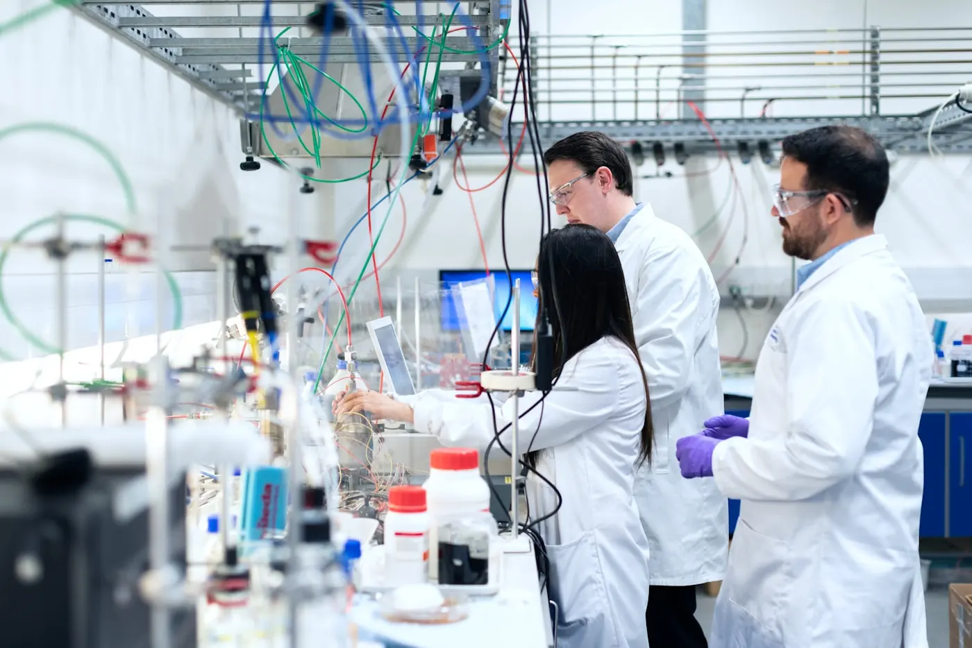 Two scientists in lab coats talking over instrumentation on a bench