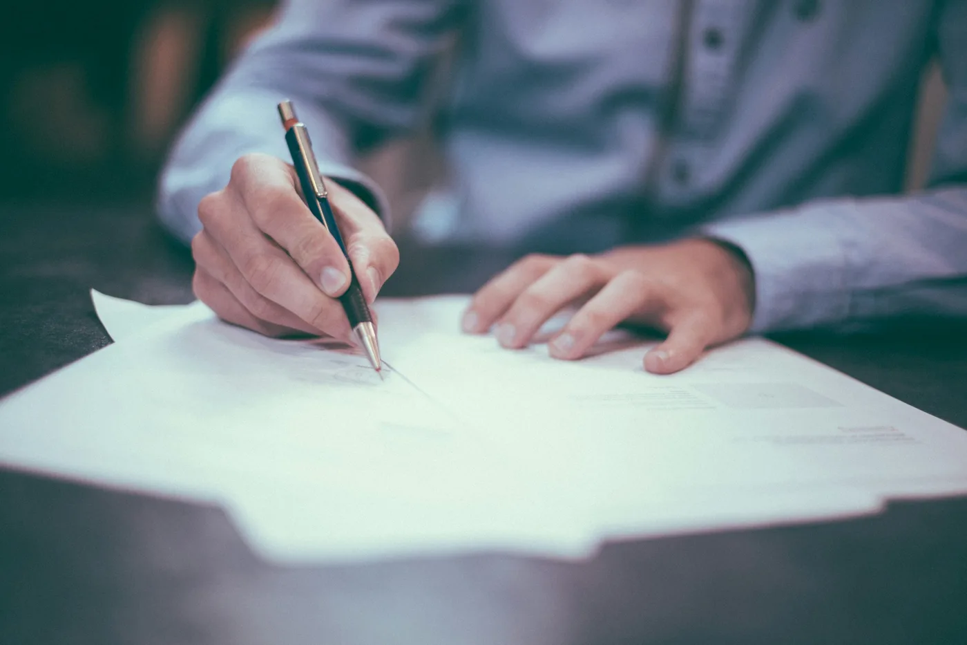A person working through a printed document with a pen in hand.