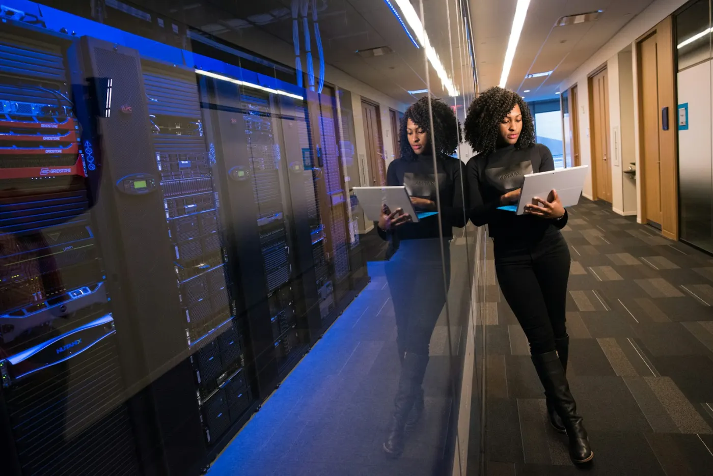Engineer reviewing work on a laptop beside server racks
