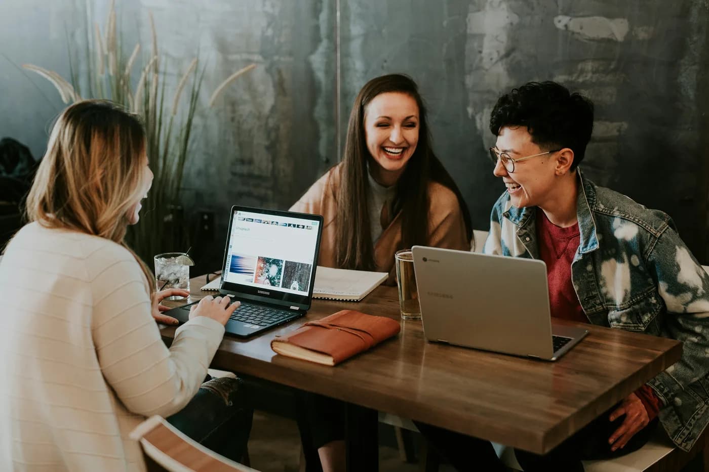Three graduates working together over laptops and notebooks.