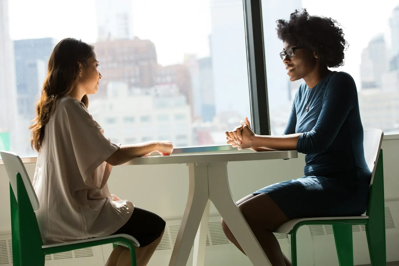 A candidate and an interviewer talking across a small table by a window